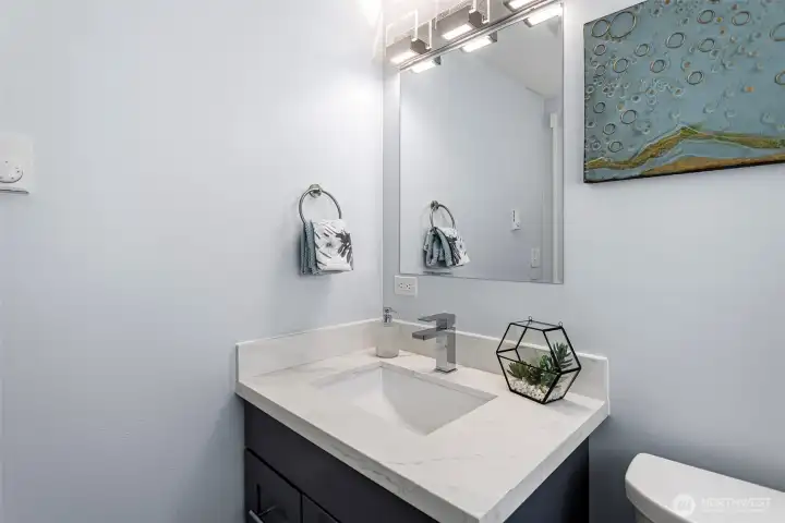 The primary wing's half bath. Quartz counter, modern fixtures, and its own window for natural light.