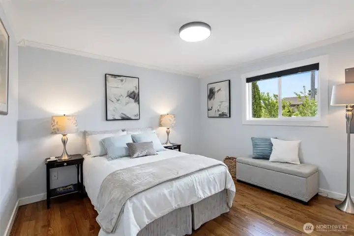 Crown molding returns. Bedroom 4, hardwood floors, street-facing window with trees.