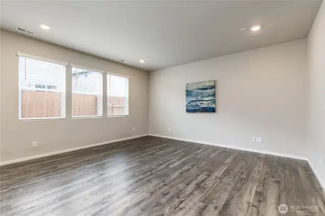 Large living room with bright windows overlooking the back yard