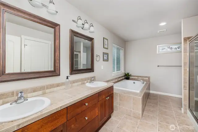 Double sinks, deep tub and tiled shower in this spacious master bath with natural light from the large window.