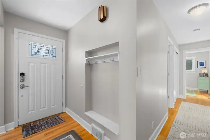 Bright, welcoming foyer with custom built-in nook and hardwood floors
