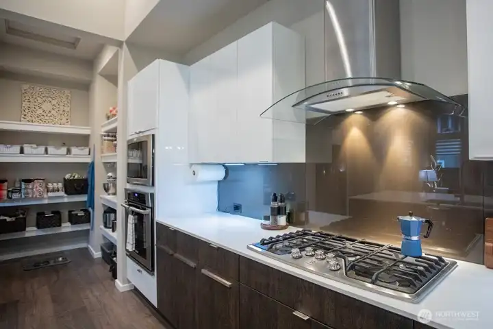 gas cooktop with wall oven and built in microwave.  Butlers pantry beyond