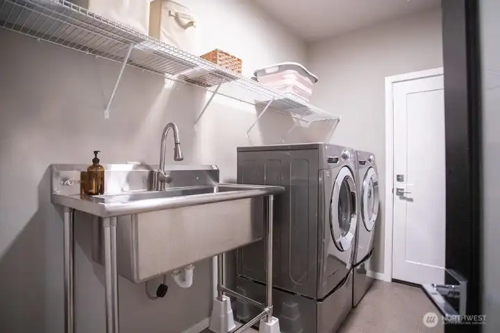 Laundry room with large sing and access to the garage beyond.  Washer and dryer stay