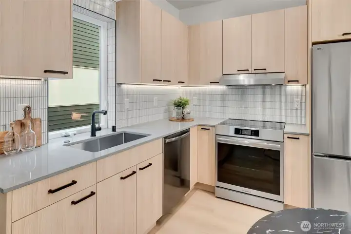 Contemporary Seattle kitchen with tile backsplash, under cabinet lighting and streamlined storage.