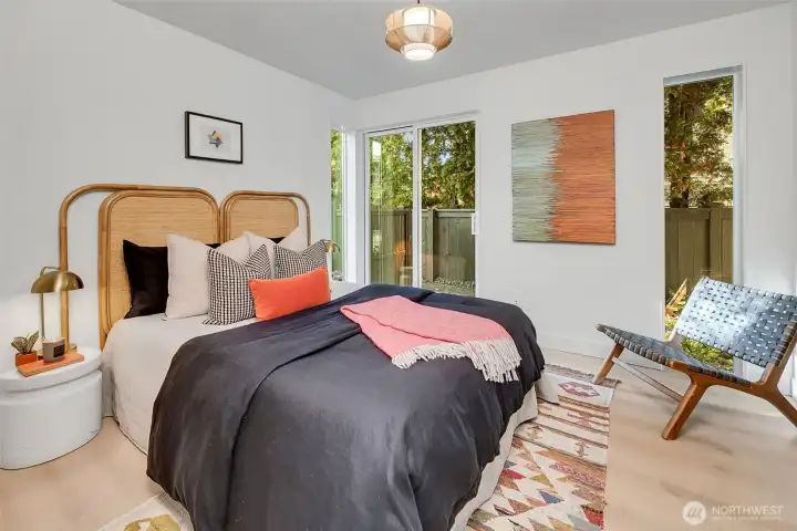 Light-filled lower-level bedroom featuring large windows & slider to patio—perfect for guests or work-from-home.