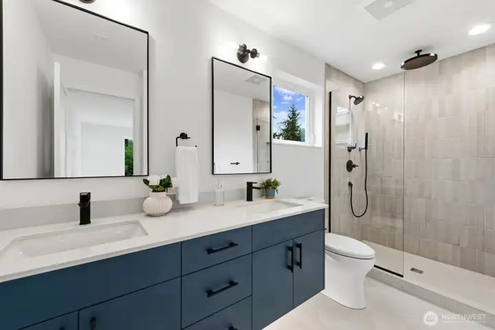 Spa-like bathroom with dual vanities, quartz counters, heated floors, and rainfall shower head.