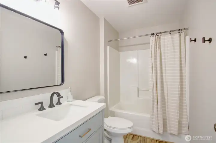 Full bathroom off of hall between bedrooms 2 & 3. New vanity, quartz counter, faucet, mirror & light fixture.