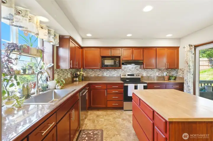 Large stainless steel sink, granite counter tops and island with butcher block.