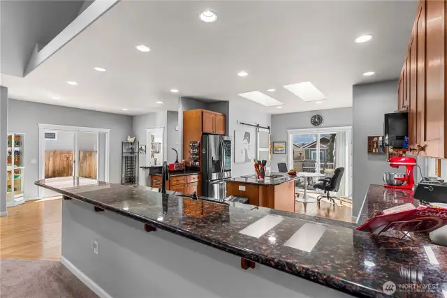 Look at all of the space for seating at this long kitchen counter with slab granite countertop.
