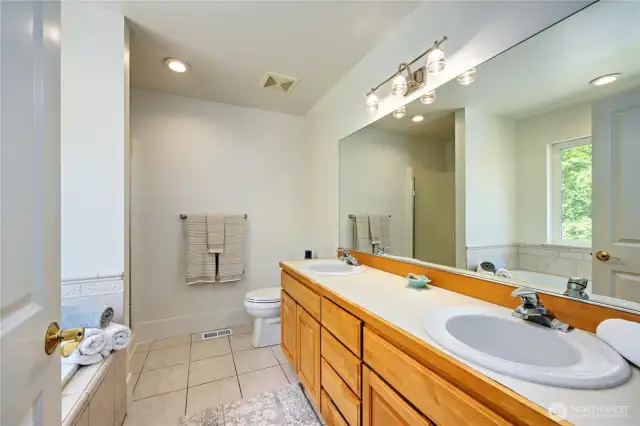 Five piece primary bath with tub, shower, double sinks and tile floor.