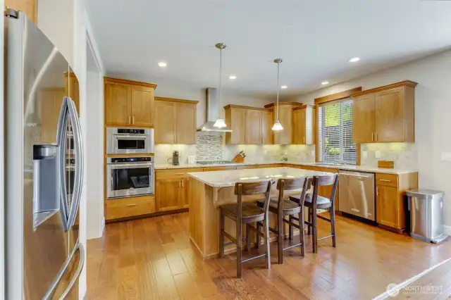 Spacious and functional kitchen with stainless steel appliances, an island with easting space.