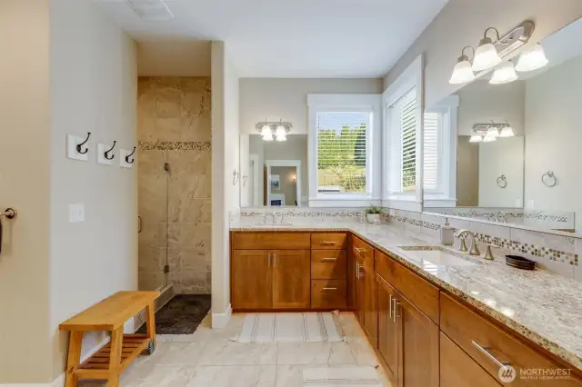 Large adjoining bathroom with private shower area, double sinks, extensive vanity space, & undercabinet lighting for night.