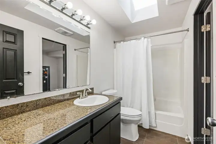 Bright, spacious full bath with skylight—door to the right opens to the primary bedroom.
