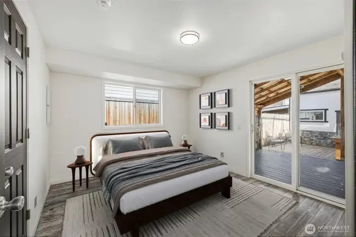 Virtual Staged-Primary bedroom with sliding glass doors leading to covered deck in backyard.