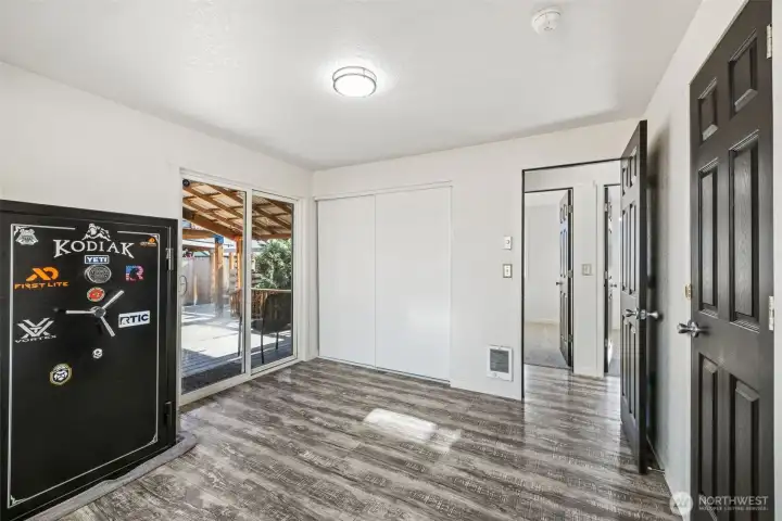 Primary bedroom with sliding glass doors leading to covered deck in backyard. Note door on left leads to full bathroom. Safe will be removed prior to closing.