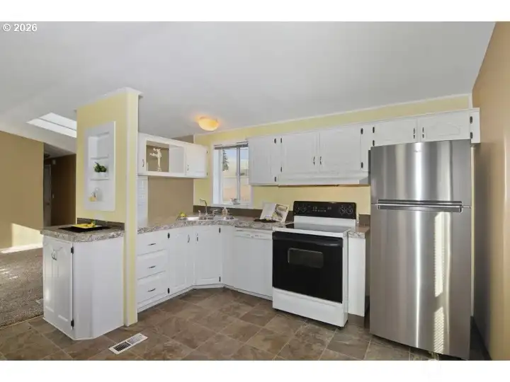 Kitchen featuring oven and dishwasher with stainless steel refrigerator.