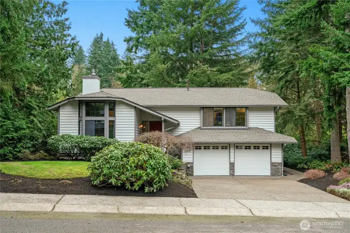 Classic Bellevue architecture surrounded by mature trees and lush landscaping for a private Northwest setting.