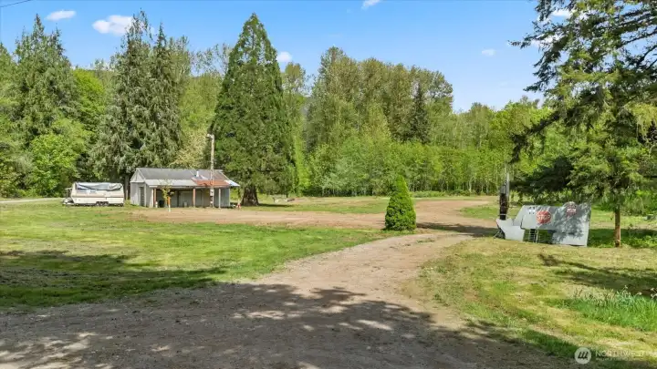Former manufactured home sat to right of garage in dirt area. Septic drainfield is in grass area to left of this driveway.