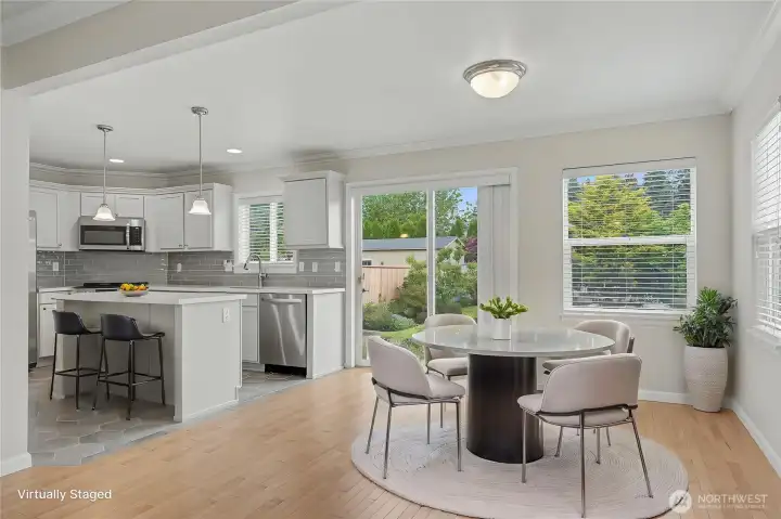 View of your dining room and kitchen from the living room, I love the large windows & patio doors allowing in all the light. ***Virtually Staged***