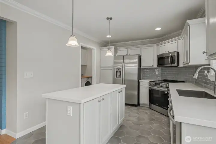 Kitchen view from dining, updated with Quartz countertops and included stainless steel appliances, full-tile backsplash as well! Utility room with your included washer & dryer upper left.