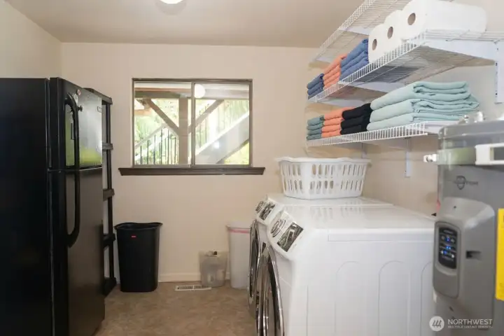 Utility room on the lower level with sink, storage, updated water heater and extra fridge.  Updated flooring in the utility room and lower level hallways.