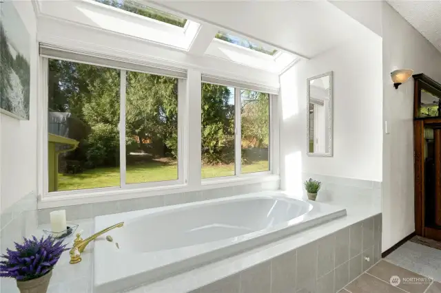 Enjoy a warm bubble bath in large jetted  soaking tub with views of private yard and flowering bushes.