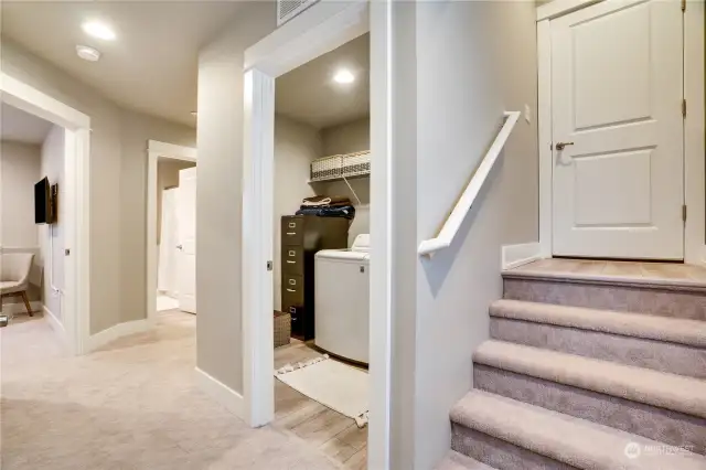 Stairs to garage entry with convenient laundry and storage to the right