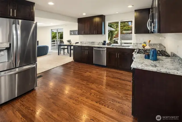 The thoughtfully renovated kitchen boasts granite countertops, custom cabinetry, stainless steel appliances—including a 5-burner gas range—and an adjoining dining area with built-in cabinets, ideal for entertaining or everyday ease.