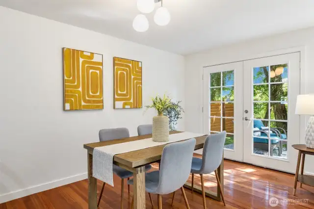Dining room area with inviting lookout through French doors to patio and serene, green backyard.