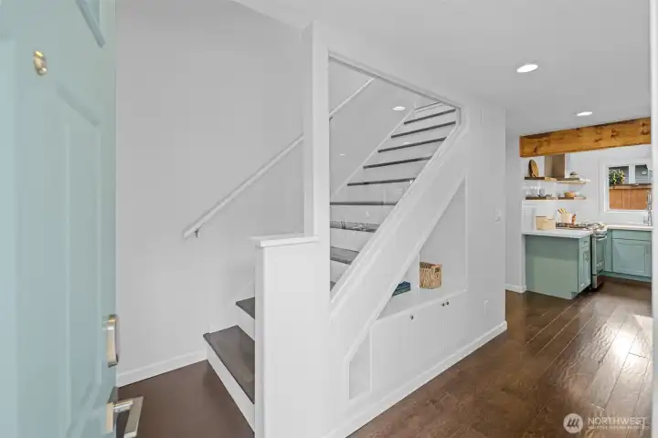 Step inside to a bright grand entry where fresh soft white walls and ceilings create an uplifting welcome that flows throughout the home. The glass stairwell wall adds a sleek modern and feel opening to a view toward the main living spaces. The front door’s soft, designer sage-green finish ties seamlessly into the kitchen’s coordinated color palette, creating a cohesive look from the moment you enter. The charming four-panel door features a multi-pane window inset, illuminating the foyer in refreshing daylight. The updated brushed-nickel hardware and a smart keypad lock, completes this stylish first impression.