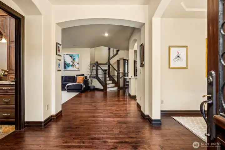 Entry with large doors: Welcoming foyer with rich flooring flowing into the main level, anchored by a graceful staircase.