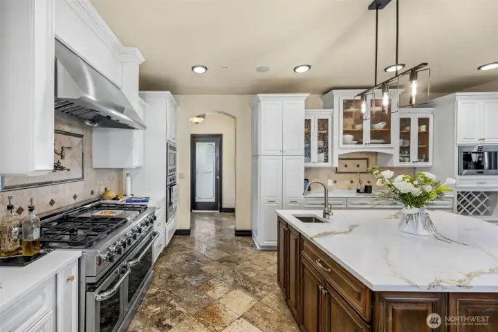 Main Floor Kitchen: Professional-grade range and hood anchor the kitchen, complemented by crisp white cabinetry.