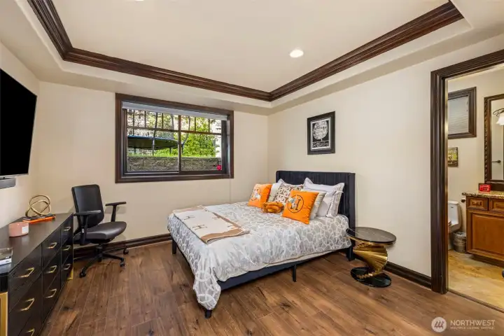 Lower level bedroom: Spacious lower-level bedroom suite with rich wood trim, abundant natural light, and serene outlook.