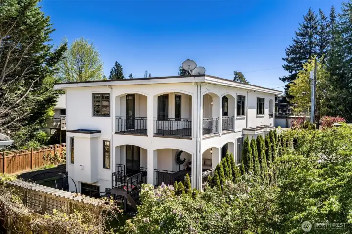 Exterior back view: Striking rear elevation showcasing the home's balconies, classical columns, and meticulous landscaping.