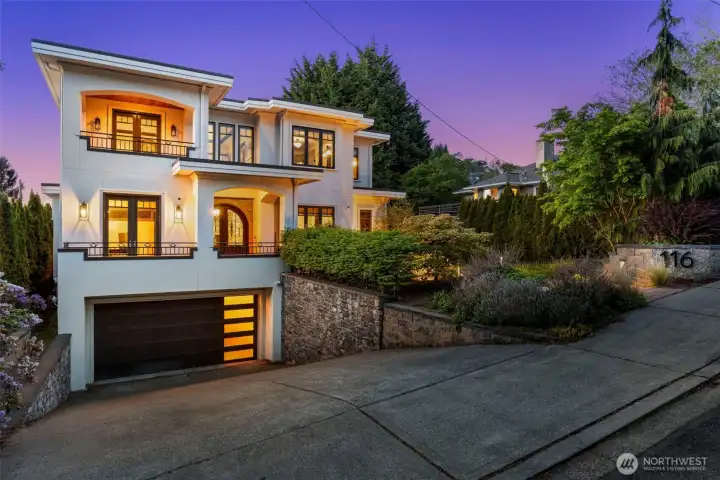 Front photo: Three-story-inspired residence glowing at twilight, framed by mature landscaping.