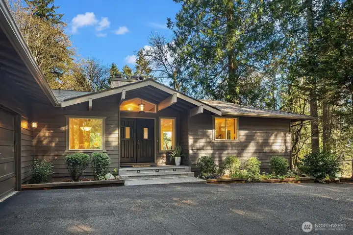 A grand covered front porch framed by towering evergreens creates a warm and inviting entry, setting the tone for the elegance found throughout this home. The classic Northwest craftsman-style façade, rich exterior finishes, and manicured landscaping offer outstanding privacy and undeniable curb appeal.