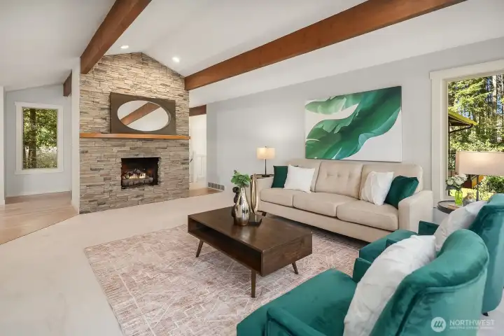 This inviting view of the living room showcases the cozy gas fireplace set against a beautiful stone surround, serving as a stunning focal point for the space. Complemented by elegant beamed ceilings, new designer carpet, and stylish finishes throughout, this warm and sophisticated living area is truly the heart of the home.
