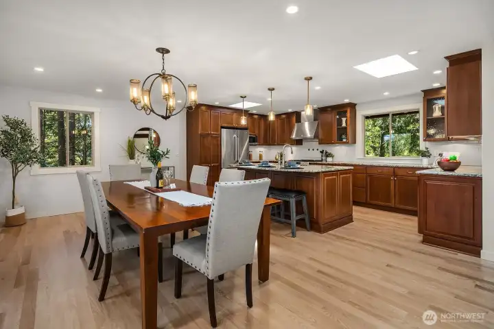The open-concept dining area flows effortlessly into the gourmet kitchen, featuring refinished hardwood floors, an elegant chandelier, and abundant natural light streaming through large windows. This seamless connection between living and dining spaces makes it ideal for both everyday meals and entertaining guests.