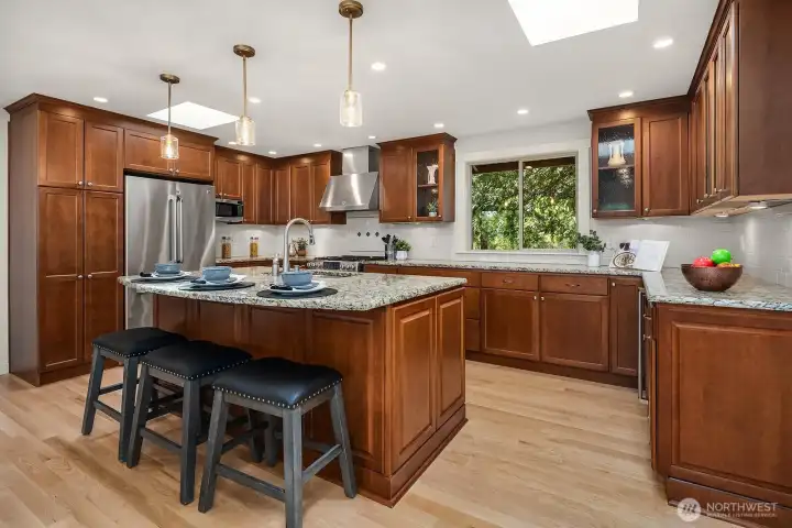 This beautifully updated gourmet kitchen features rich warm cabinetry, a large center island with bar seating, stainless steel appliances, and updated designer lighting — offering both exceptional functionality and stylish appeal. Ample storage and generous counter space make this kitchen a true chef's dream, perfect for cooking and entertaining alike.