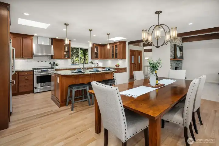 This elegant dining area features a stunning statement chandelier and a spacious table perfectly positioned to take in the open sightlines straight through to the gourmet kitchen beyond. The refinished hardwood floors, fresh interior paint, and seamless open-concept layout make this space ideal for both intimate dinners and large gatherings.