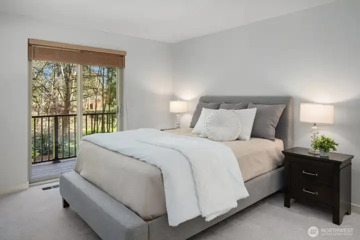 This beautiful alternate view of the primary suite highlights the direct access to the private deck through large sliding glass doors, filling the room with gorgeous natural light and offering a seamless indoor-outdoor connection. Fresh paint, new designer carpet, and elegant finishes make this tranquil retreat truly feel like a five-star escape.