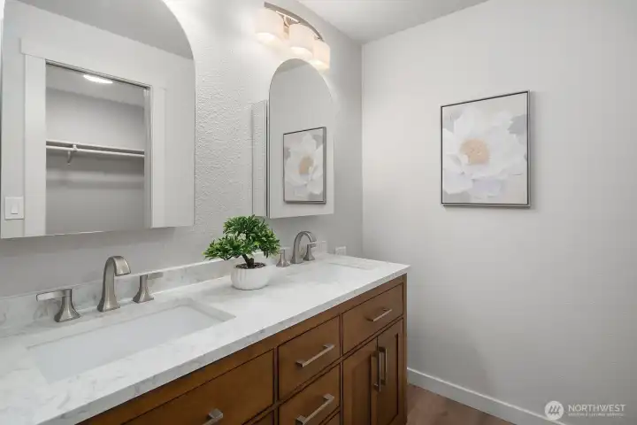 This beautifully updated full hall bath features a rich wood vanity with elegant marble-style countertops, a large mirror, and fresh neutral finishes that create a clean, modern aesthetic. Thoughtfully designed and move-in ready, this stylish bath serves the additional main-level bedrooms with both comfort and sophistication.