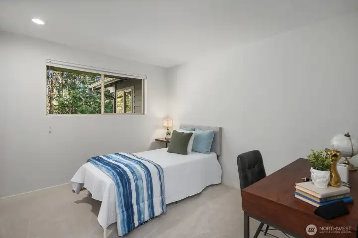 This welcoming lower level bedroom offers a flexible and functional space, featuring fresh new carpet, crisp white walls, and a bright window that brings in natural light despite its lower level location. As part of the home's versatile ADU, this room is ideal for guests, extended family, or a dedicated home office setup.