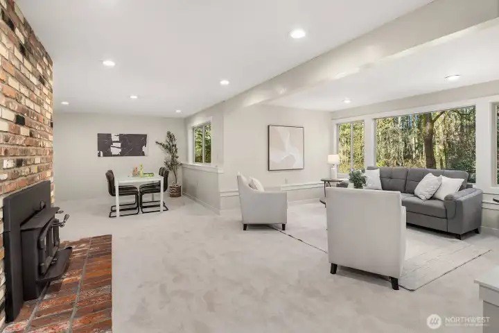 The lower level living room is anchored by a charming brick fireplace, creating a warm and inviting atmosphere that makes this ADU space feel like a true home within a home. With new carpet, fresh paint, and abundant natural light from large windows, this expansive space is perfect for relaxed living and entertaining.