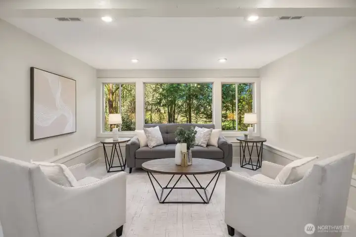 This bright and elegant lower level sitting area features a sophisticated seating arrangement, recessed lighting, and a large picture window that floods the space with natural light and garden views. The refined finishes and generous proportions of this room further underscore the exceptional quality and versatility of the home's ADU living space.