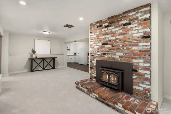 This striking lower level space showcases a dramatic floor-to-ceiling stacked stone fireplace as its centerpiece, adding warmth, texture, and a bold design statement to the ADU's living area. The open layout, new carpet, and recessed lighting create a cozy yet sophisticated atmosphere perfect for relaxing or entertaining year-round.