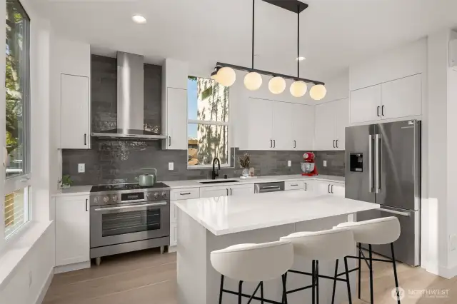 A true chef's kitchen with a bold tile backsplash, statement lighting, and custom cabinets—style and substance, side by side.