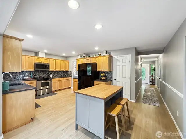 Updated kitchen with natural stone countertops, granite sink, modern backsplash and oak cabinets, gas range.