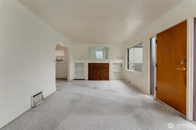Large front window allows for daylight in the classic living room with Batchelder fireplace.