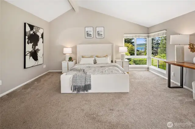 Retreat to the primary bedroom with vaulted ceilings, sitting area, cozy fireplace, wall of windows, and lake views.